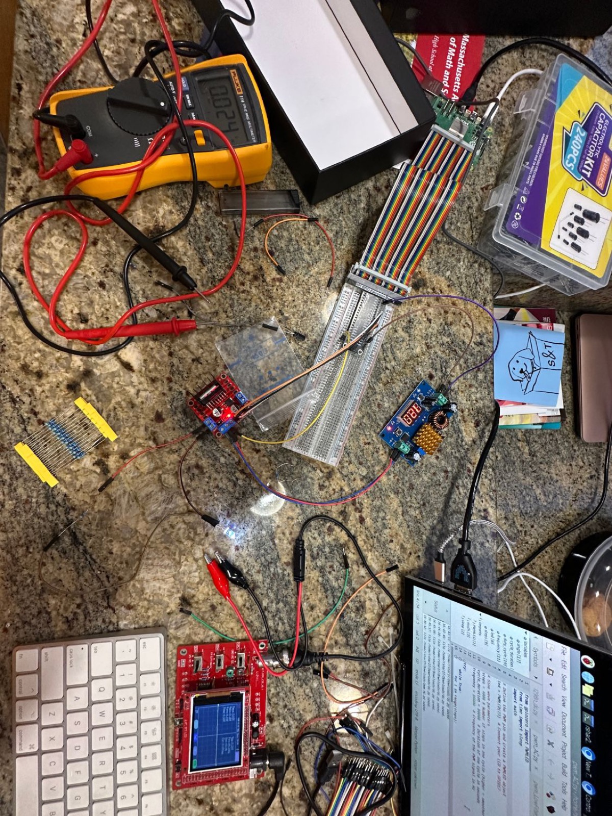 Overhead view of an electronics workbench with a multimeter, breadboard and oscilloscope