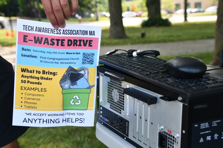 Holding a Tech Awareness Association e-waste drive flyer beside a donated desktop tower