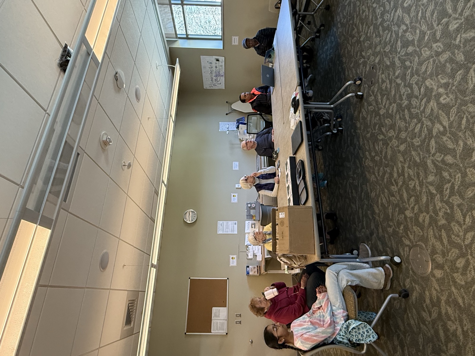 Seniors seated around tables during a technology help session