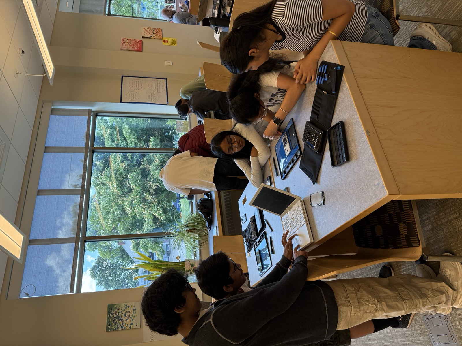 Students repairing laptops and tablets together at a library table
