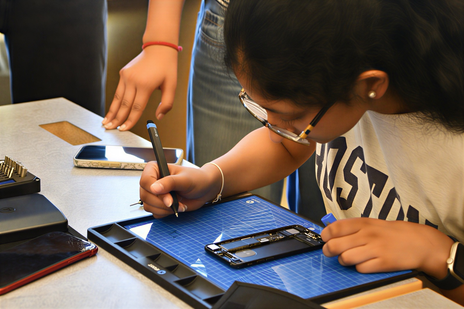A student documenting a phone repair on a blue FixMat
